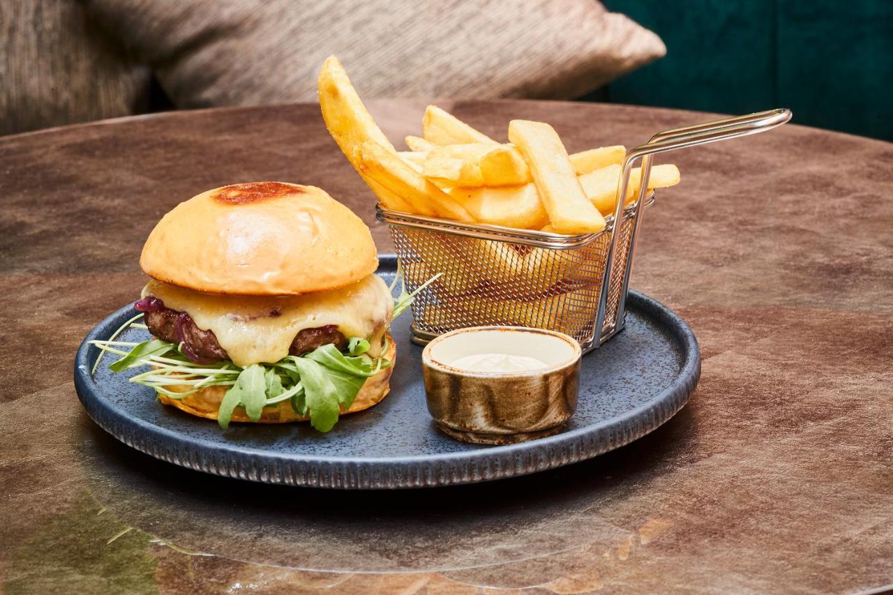Steigenberger Hotel Herrenhof Vienna Exterior photo The photo shows a delicious meal consisting of a hamburger and French fries. The hamburger is served on a round plate and features a soft, shiny bun filled with ingredients like a beef patty, possibly cheese, lettuce, and other toppings. Next to the 
