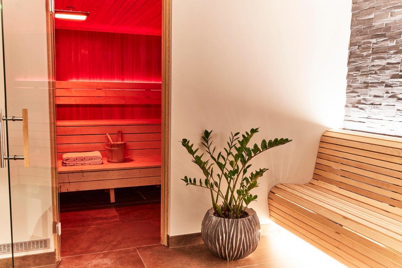 Steigenberger Hotel Herrenhof Vienna Exterior photo The photo shows a serene spa or sauna area. On the left, there is a wooden sauna room with a red interior lighting. Inside the sauna, there is a wooden bench and a bucket, typically used for pouring water over hot stones to create steam. To the right
