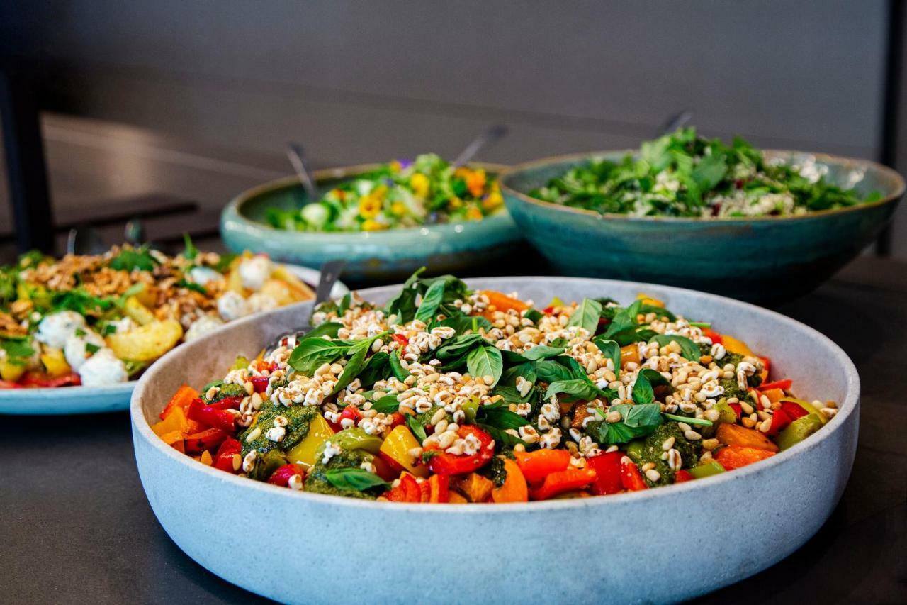 Steigenberger Hotel Herrenhof Vienna Exterior photo The photo shows a variety of colorful salads displayed in large bowls. In the foreground, there is a round bowl filled with a vibrant salad that includes mixed greens and chopped vegetables, topped with crunchy elements. In the background, there are 